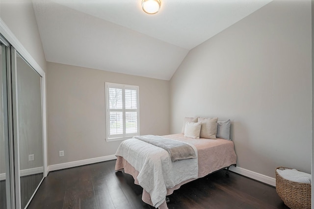 bedroom with a closet, baseboards, vaulted ceiling, and dark wood finished floors