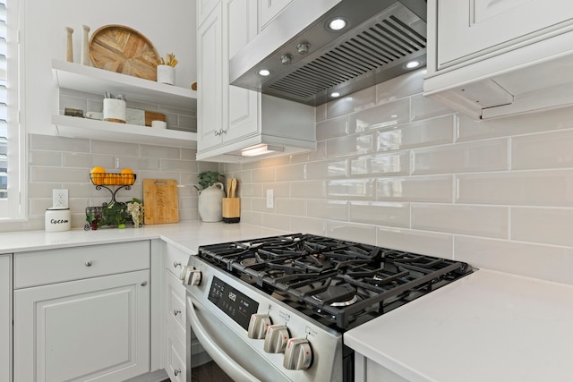 kitchen with backsplash, extractor fan, stainless steel range with gas stovetop, white cabinets, and open shelves