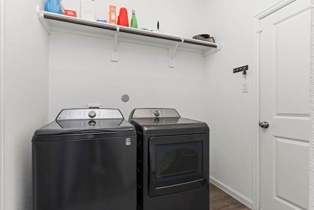 clothes washing area with laundry area, dark wood-style floors, baseboards, and washer and clothes dryer