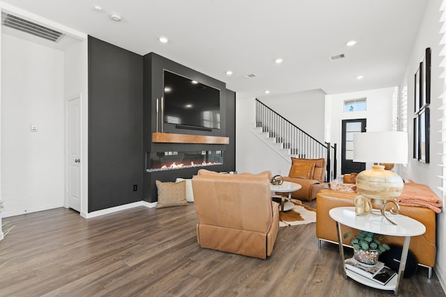 living area featuring visible vents, wood finished floors, and a glass covered fireplace