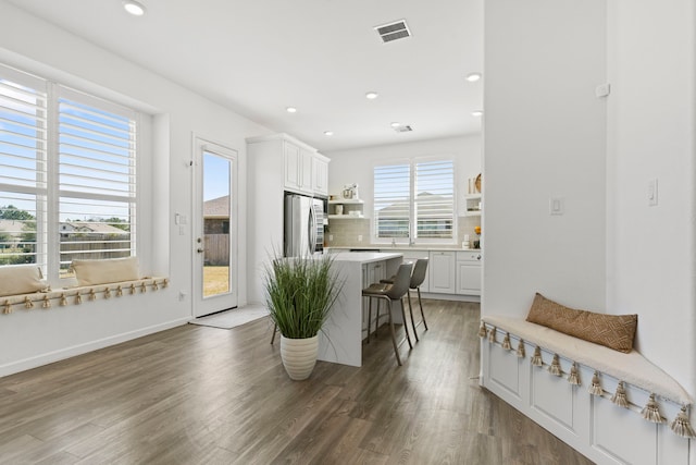 kitchen featuring visible vents, open shelves, freestanding refrigerator, a kitchen bar, and backsplash