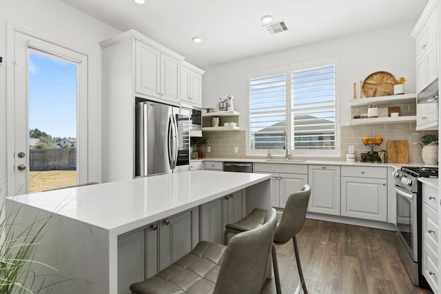 kitchen with visible vents, a healthy amount of sunlight, open shelves, stainless steel appliances, and a sink