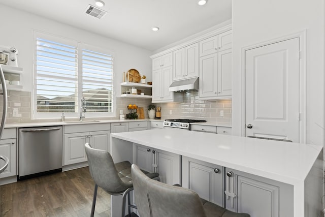 kitchen with visible vents, a sink, stove, under cabinet range hood, and dishwasher