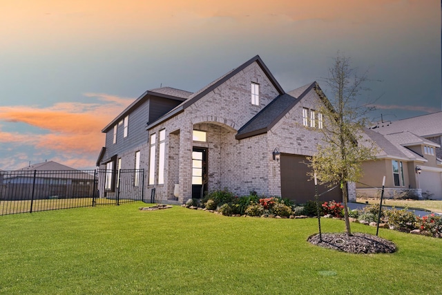 french provincial home featuring fence, a lawn, and brick siding