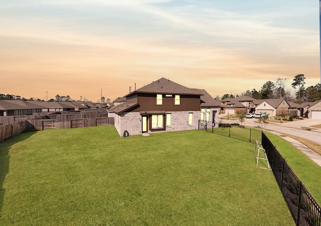 yard at dusk featuring a residential view and a fenced backyard