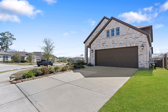 exterior space featuring fence, concrete driveway, a front yard, a garage, and brick siding