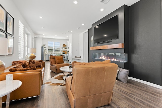 living area with a glass covered fireplace, recessed lighting, wood finished floors, and baseboards