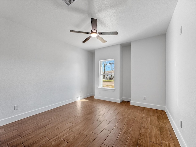 spare room featuring ceiling fan, a textured ceiling, wood finished floors, and baseboards