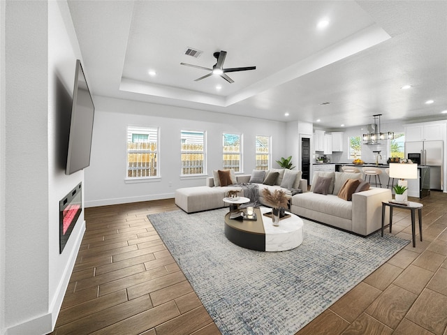 living area featuring wood tiled floor, a raised ceiling, visible vents, and a fireplace