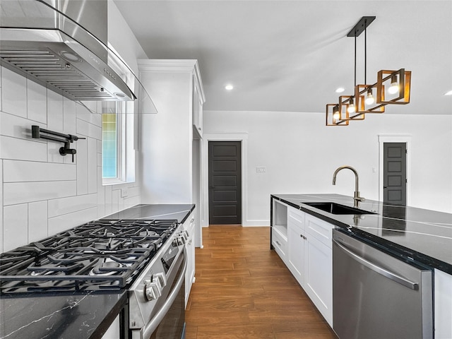 kitchen with dark wood-style floors, appliances with stainless steel finishes, white cabinetry, a sink, and wall chimney range hood