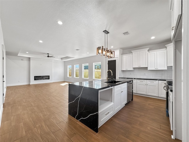 kitchen featuring a sink, visible vents, dishwasher, open shelves, and a glass covered fireplace