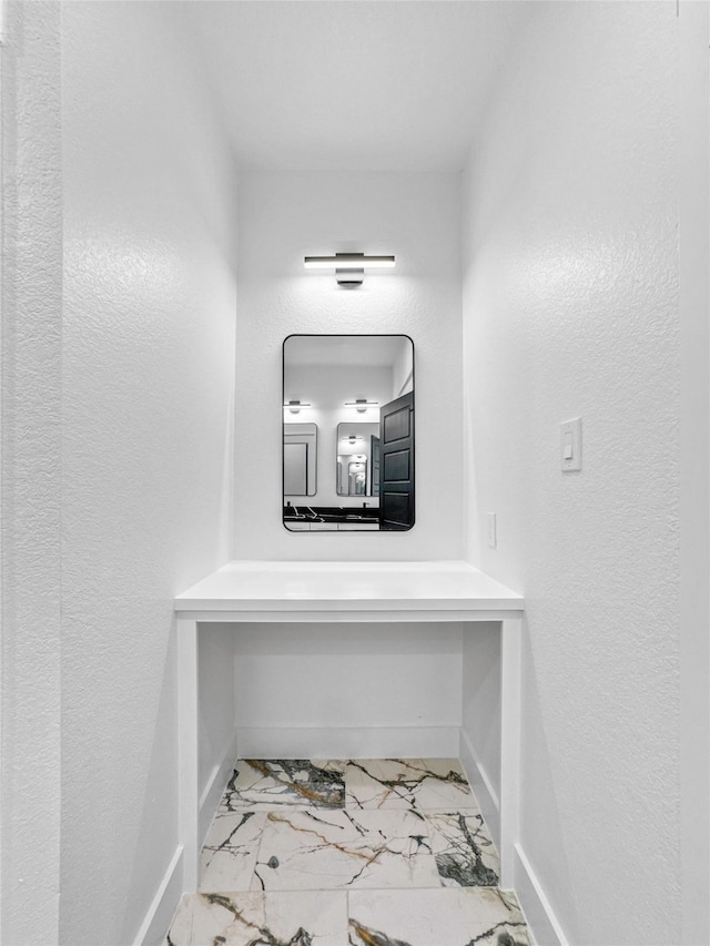 hallway featuring marble finish floor and baseboards