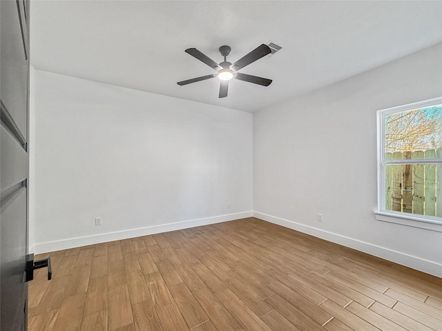 spare room with a ceiling fan, visible vents, baseboards, and wood finished floors