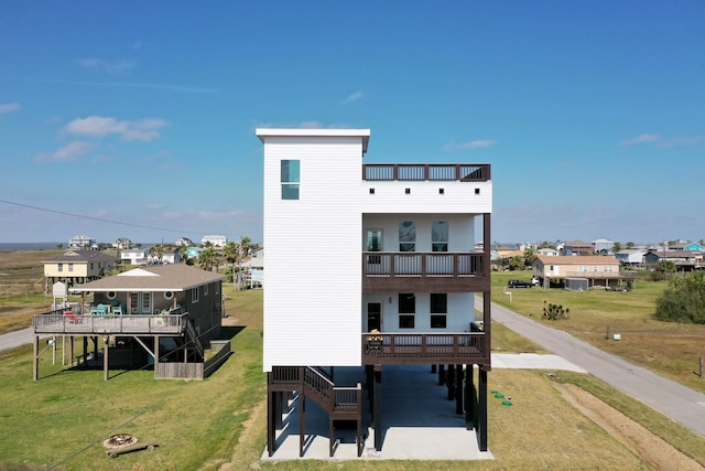 back of house with stairs, a yard, and a balcony