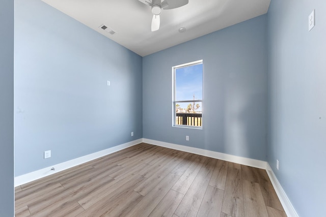 empty room featuring ceiling fan, wood finished floors, visible vents, and baseboards