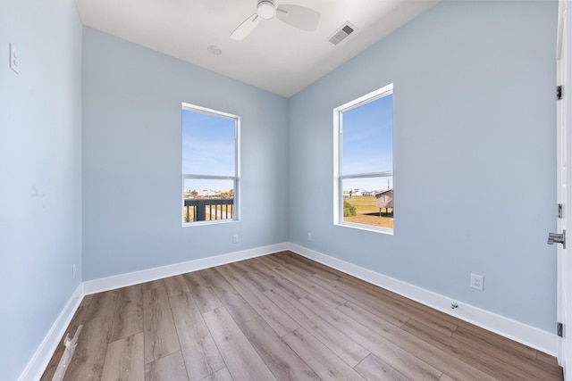 spare room with a wealth of natural light, visible vents, baseboards, and wood finished floors