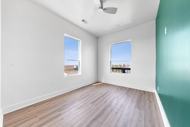 unfurnished room featuring ceiling fan, plenty of natural light, baseboards, and wood finished floors