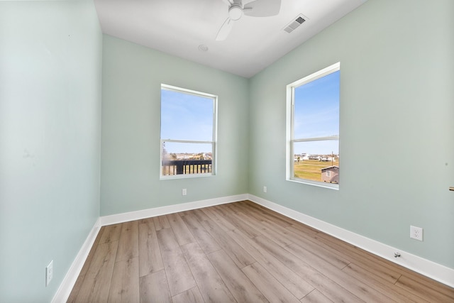 unfurnished room featuring ceiling fan, visible vents, baseboards, and wood finished floors