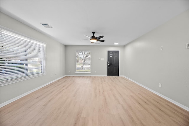 unfurnished living room featuring light wood-style floors, a ceiling fan, visible vents, and baseboards