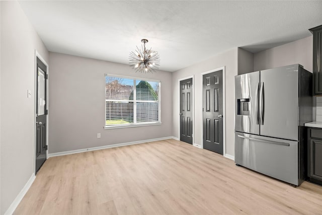 kitchen featuring light wood-type flooring, stainless steel fridge, a chandelier, and baseboards