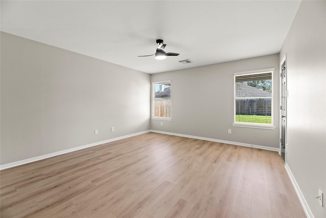 unfurnished room with light wood finished floors, plenty of natural light, visible vents, and baseboards