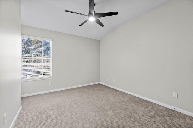 carpeted empty room featuring ceiling fan, vaulted ceiling, and baseboards