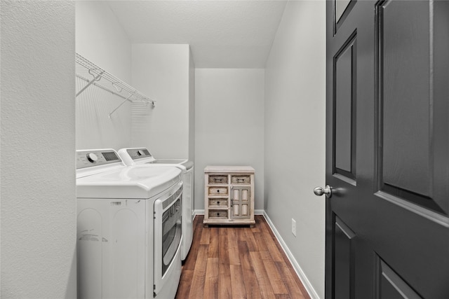 washroom featuring a textured ceiling, washing machine and dryer, laundry area, baseboards, and dark wood-style floors