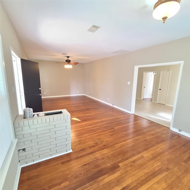 spare room with a ceiling fan, visible vents, baseboards, and wood finished floors