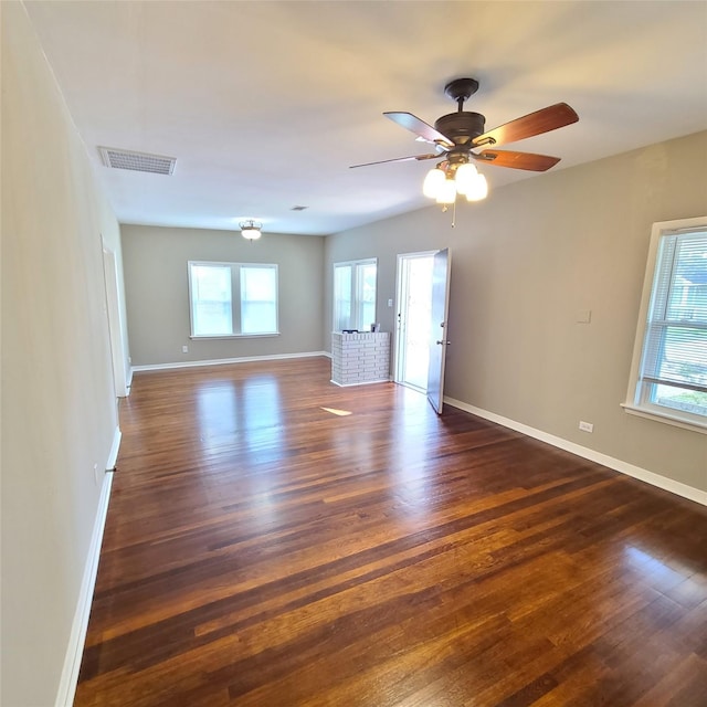 spare room with ceiling fan, baseboards, visible vents, and dark wood finished floors