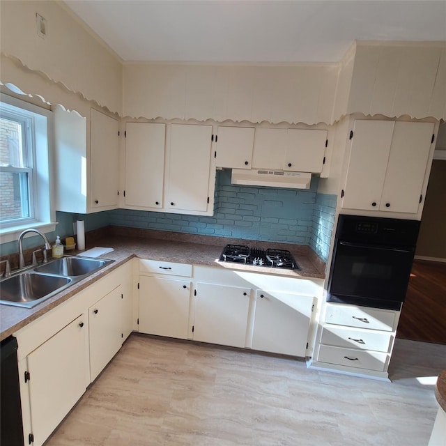 kitchen with light wood finished floors, a sink, under cabinet range hood, black appliances, and backsplash