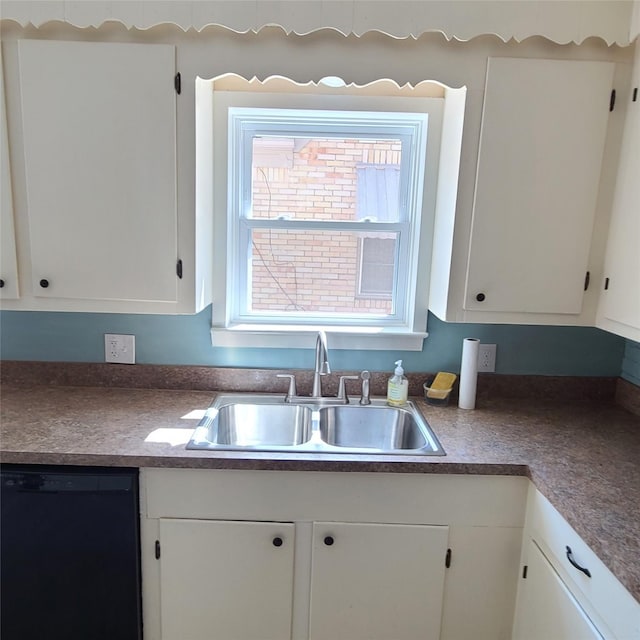 kitchen with dark countertops, black dishwasher, white cabinets, and a sink