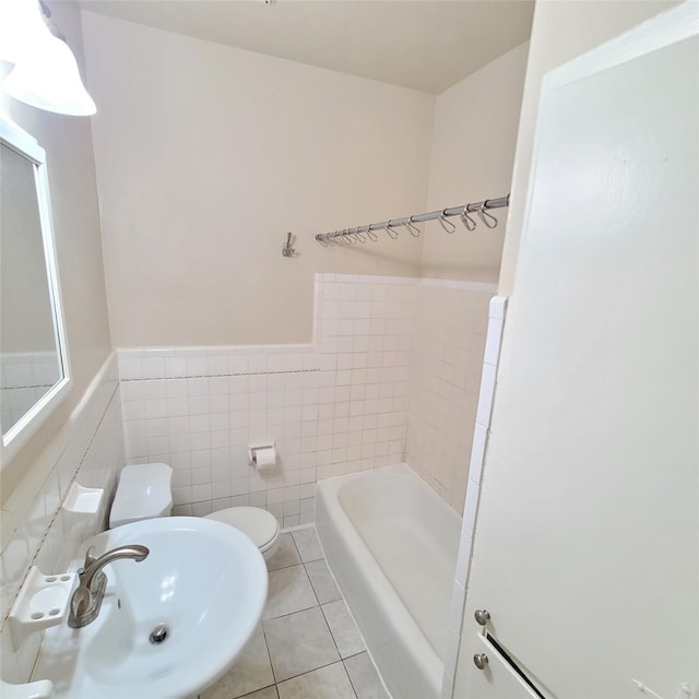 full bath with a tub to relax in, tile walls, toilet, a sink, and tile patterned floors