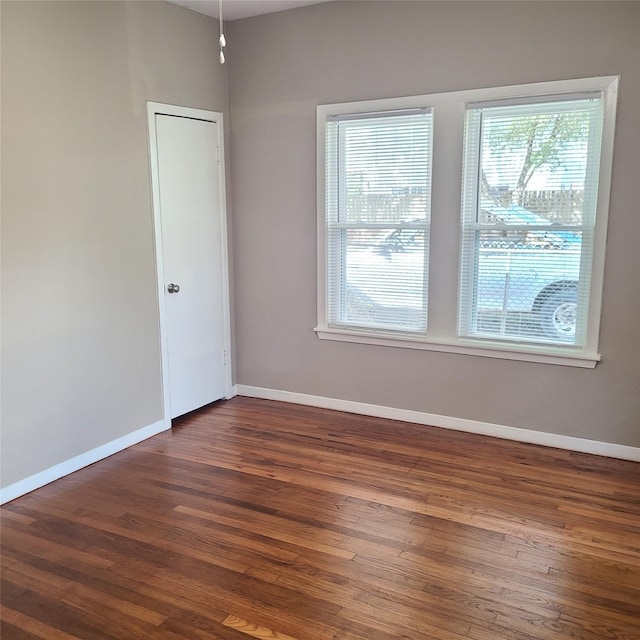 spare room with dark wood-style floors and baseboards