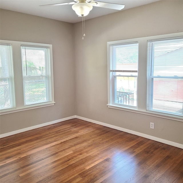 spare room featuring ceiling fan, plenty of natural light, wood finished floors, and baseboards