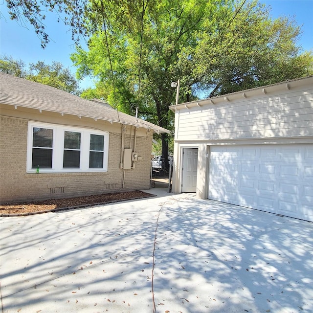 view of side of home with a garage, crawl space, brick siding, and an outdoor structure