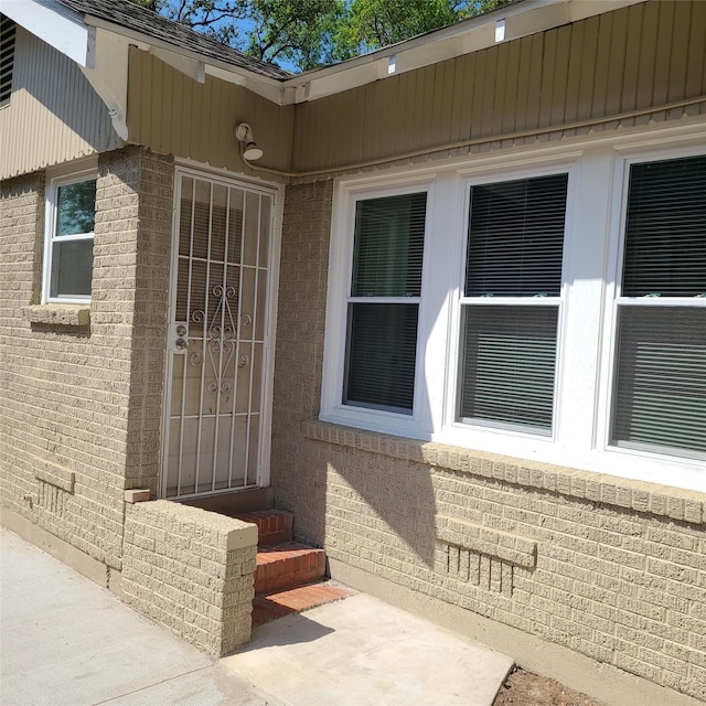 property entrance with brick siding and roof with shingles