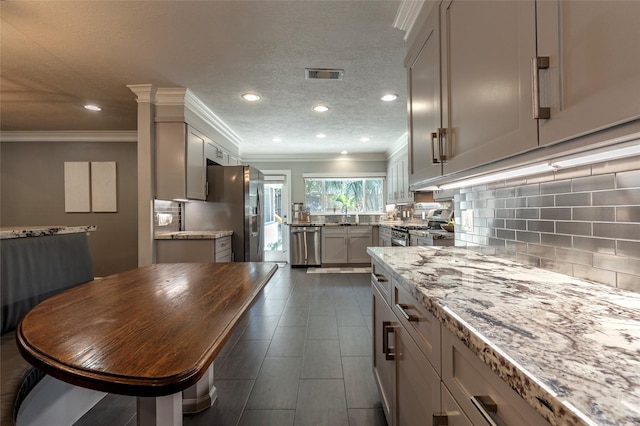 kitchen featuring tasteful backsplash, visible vents, light stone countertops, stainless steel appliances, and a textured ceiling