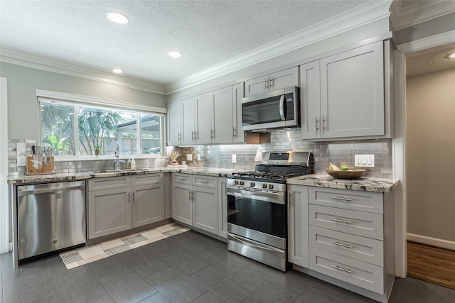 kitchen featuring stainless steel appliances, gray cabinetry, and light stone countertops