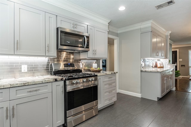 kitchen with stainless steel appliances, ornamental molding, visible vents, and baseboards