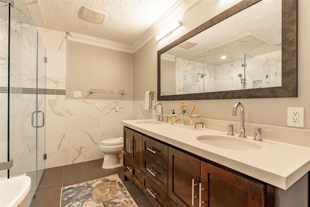 bathroom with a marble finish shower, a textured ceiling, ornamental molding, and a sink