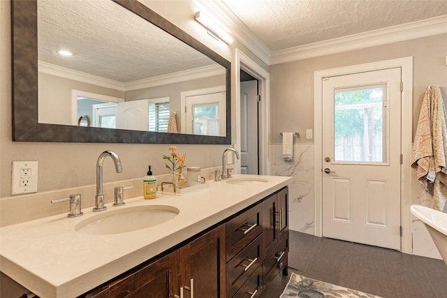 full bathroom featuring double vanity, crown molding, a textured ceiling, and a sink