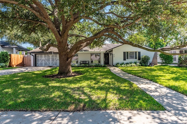 single story home featuring driveway, brick siding, a front lawn, and fence