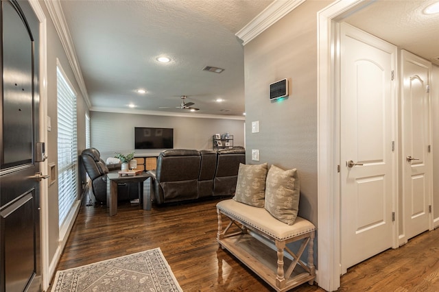 living area with a textured ceiling, ornamental molding, dark wood-type flooring, and visible vents