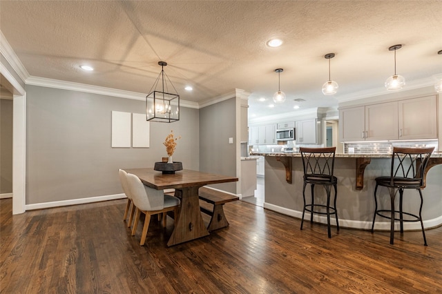 dining area featuring a textured ceiling, ornamental molding, dark wood finished floors, and baseboards