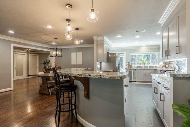 kitchen with appliances with stainless steel finishes, light stone counters, and ornamental molding