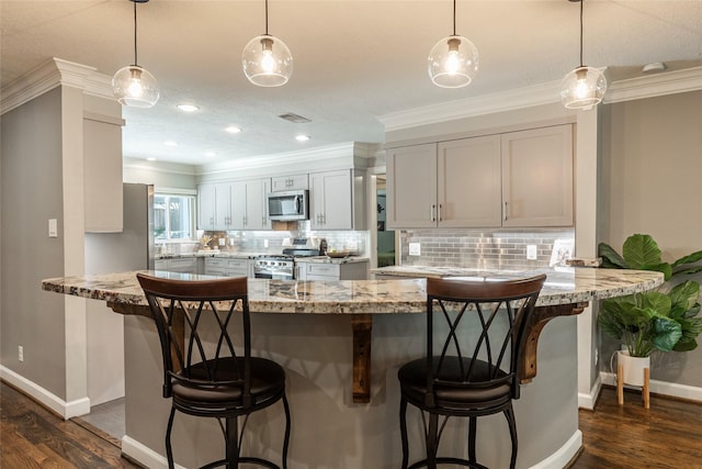 kitchen with dark wood-style floors, appliances with stainless steel finishes, a breakfast bar area, and backsplash