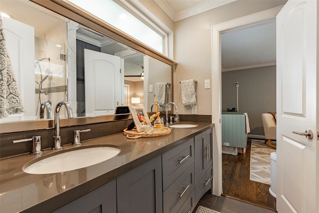 bathroom featuring crown molding, double vanity, a sink, and wood finished floors