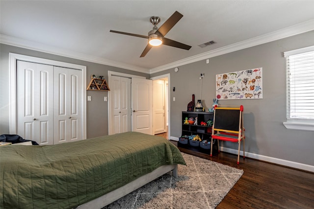 bedroom with visible vents, baseboards, ornamental molding, dark wood-style flooring, and two closets