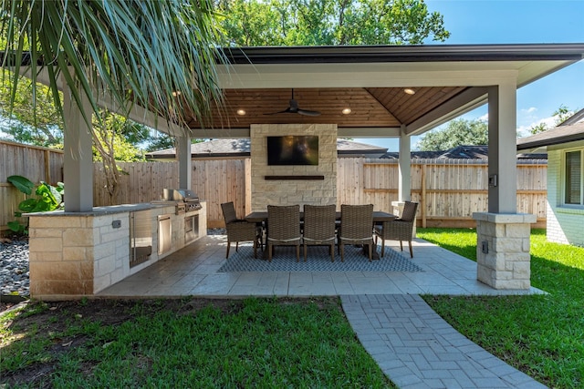 view of patio with exterior kitchen, outdoor dining area, grilling area, and fence