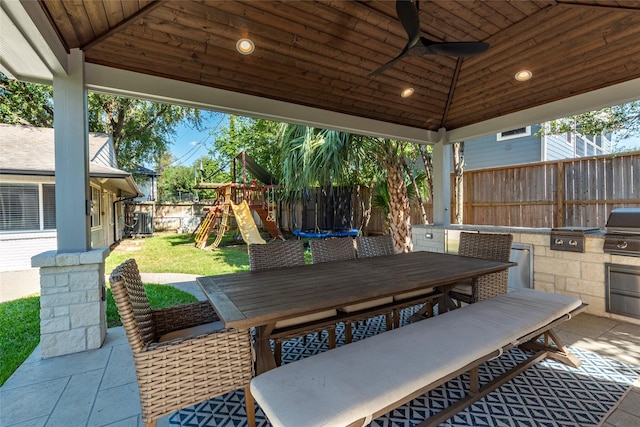 view of patio featuring a fenced backyard, a trampoline, exterior kitchen, a playground, and outdoor dining space